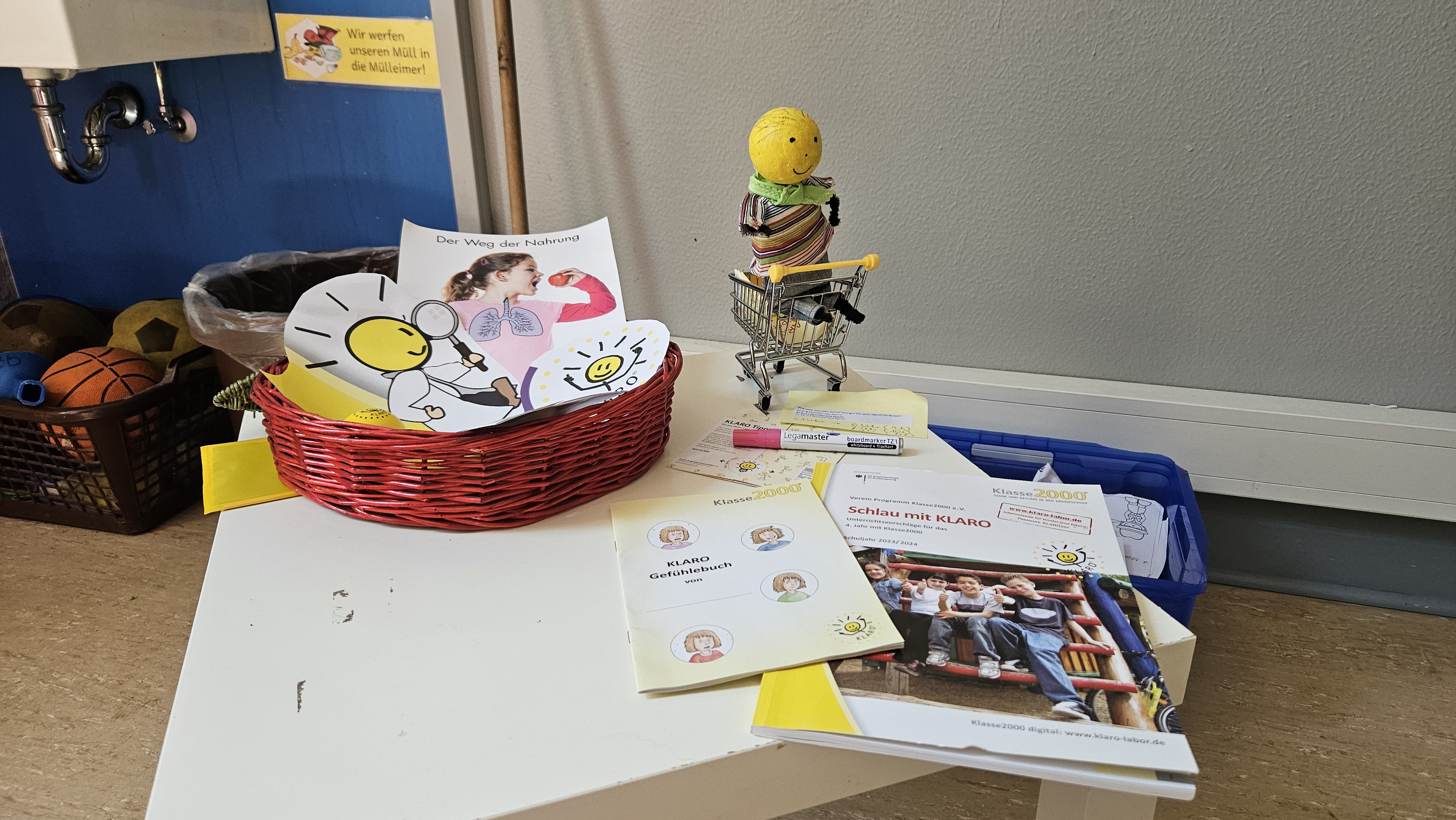 KLARO-Figur, Karten und Unterrichtshefte von Klasse2000 auf einem Tisch.