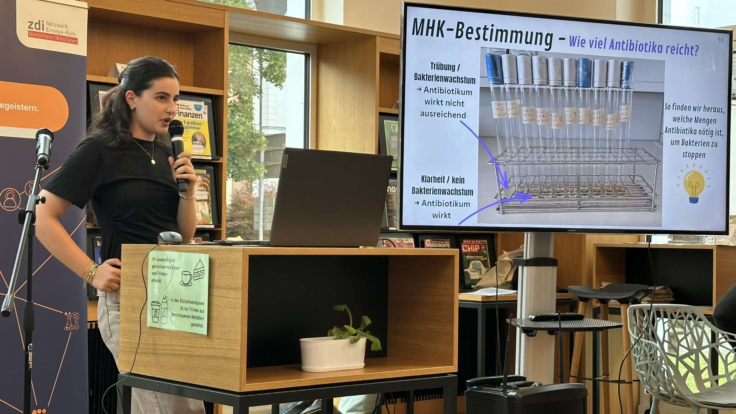 Teilnehmerin mit Mikrofon und einer Präsentation beim Science Slam der Wittener Schulen 2026.